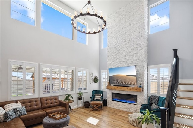 living room featuring a high ceiling, a notable chandelier, a fireplace, and light hardwood / wood-style floors