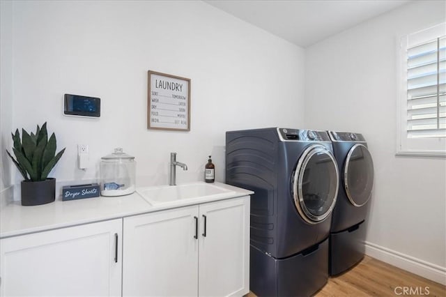 laundry area with sink, light hardwood / wood-style flooring, cabinets, and separate washer and dryer