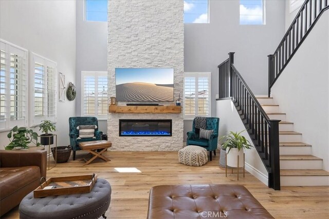 living room featuring a high ceiling, a fireplace, and wood-type flooring