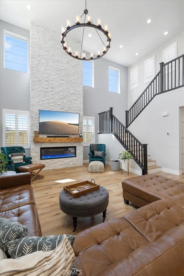 living room featuring a fireplace, hardwood / wood-style flooring, a towering ceiling, and an inviting chandelier