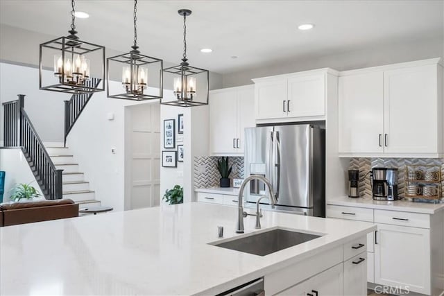 kitchen featuring backsplash, sink, white cabinetry, and stainless steel fridge