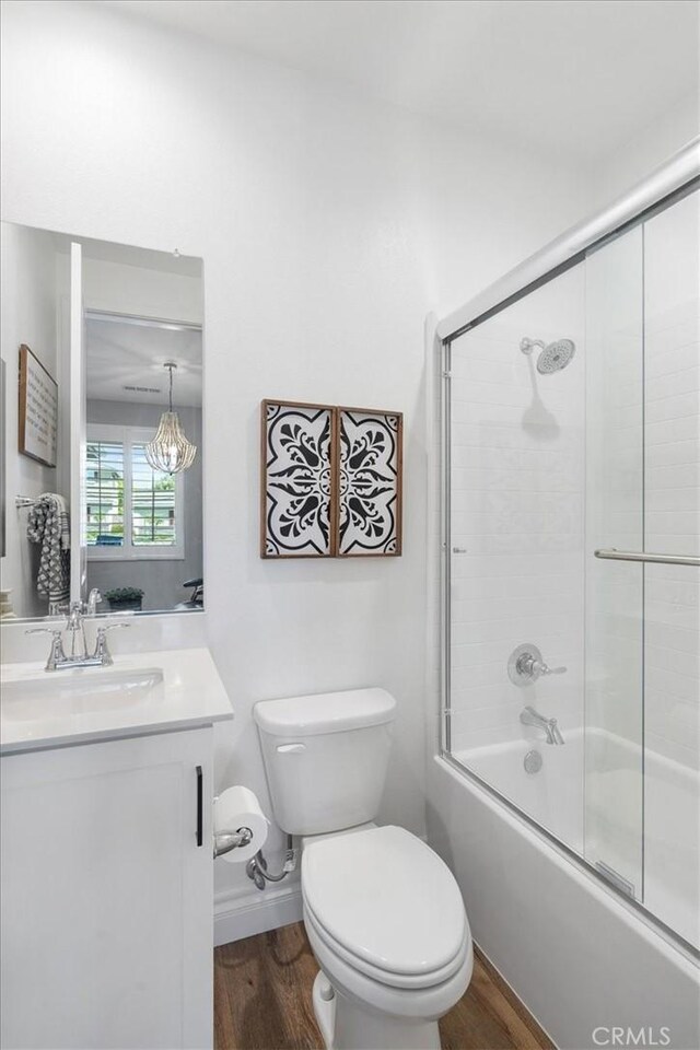 full bathroom with wood-type flooring, combined bath / shower with glass door, toilet, and vanity