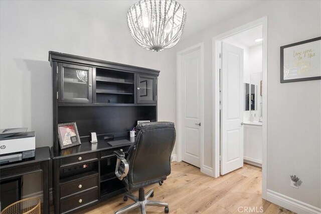 home office with light hardwood / wood-style flooring and a notable chandelier