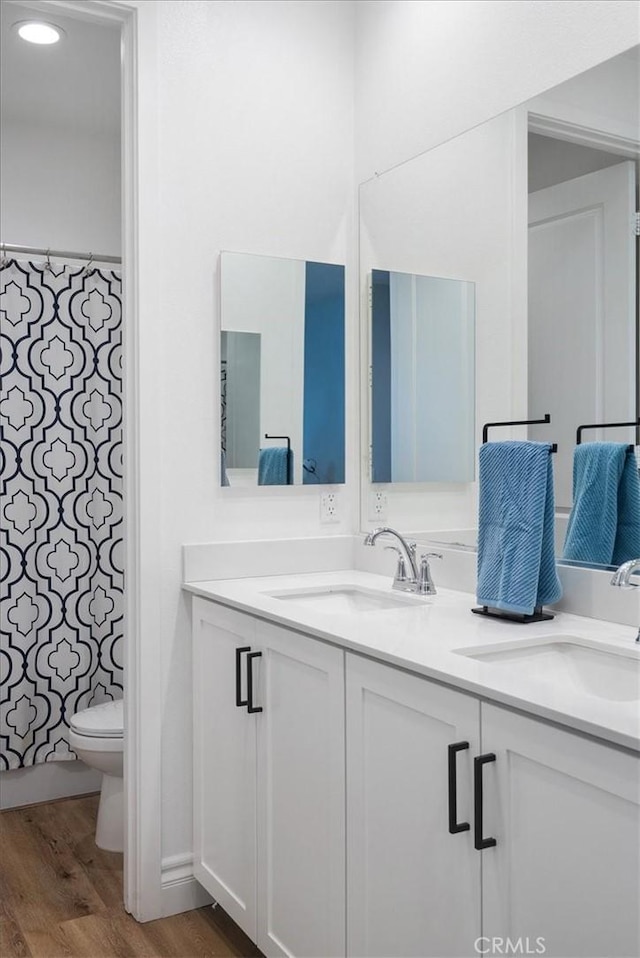 bathroom with wood-type flooring, toilet, and vanity