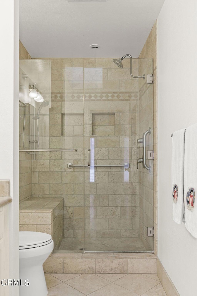 bathroom with toilet, tile patterned floors, and walk in shower