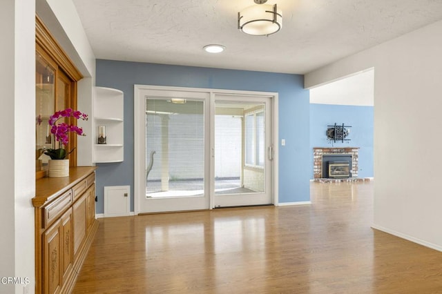 entryway featuring a textured ceiling, plenty of natural light, light hardwood / wood-style floors, and a fireplace