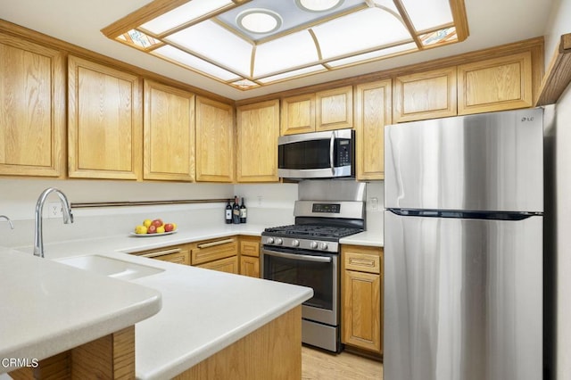 kitchen with kitchen peninsula, light brown cabinets, stainless steel appliances, and sink