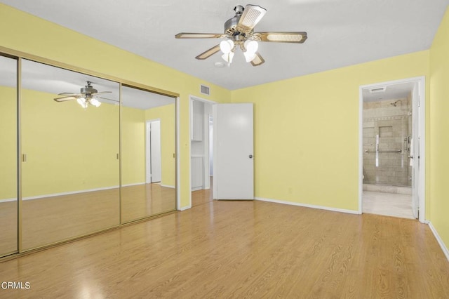 unfurnished bedroom with a closet, light hardwood / wood-style flooring, ensuite bath, and ceiling fan