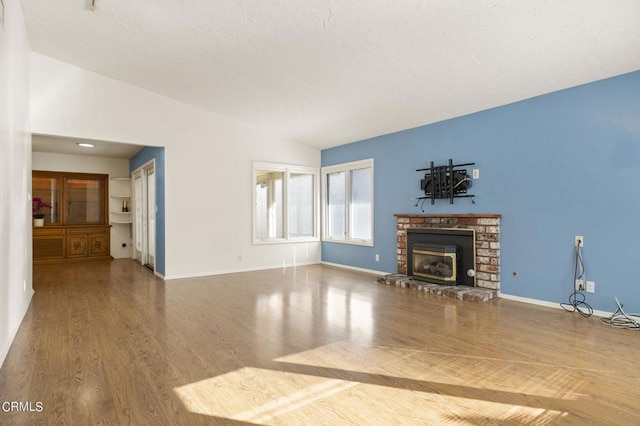 unfurnished living room with a fireplace, wood-type flooring, and vaulted ceiling