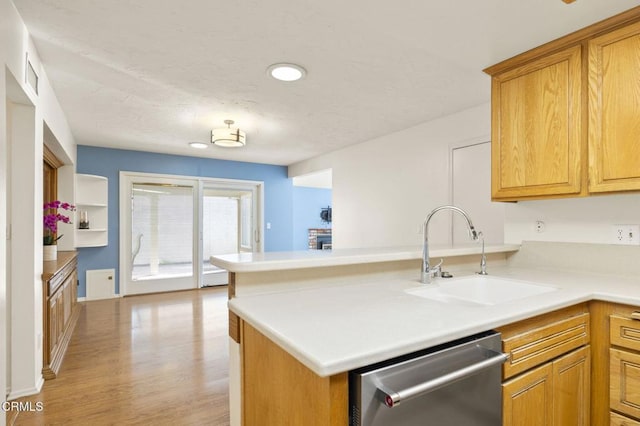 kitchen featuring stainless steel dishwasher, light hardwood / wood-style floors, kitchen peninsula, and sink