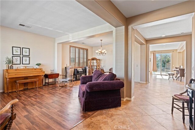 living room featuring a notable chandelier, light hardwood / wood-style floors, and a textured ceiling