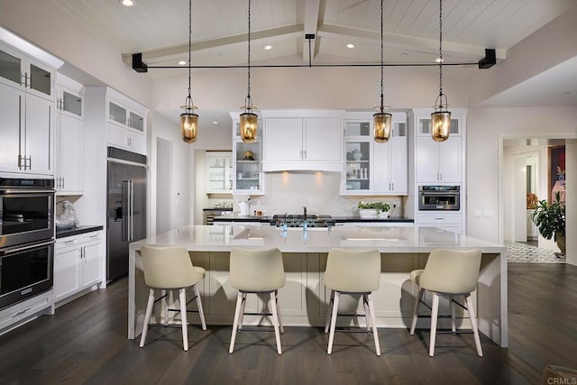 kitchen with hanging light fixtures, decorative backsplash, a spacious island, and appliances with stainless steel finishes