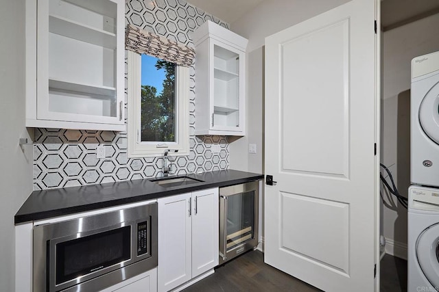 kitchen featuring white cabinetry, stainless steel microwave, wine cooler, and stacked washer and clothes dryer