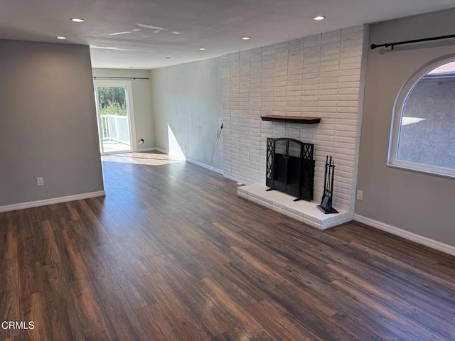 unfurnished living room featuring a brick fireplace and dark hardwood / wood-style floors