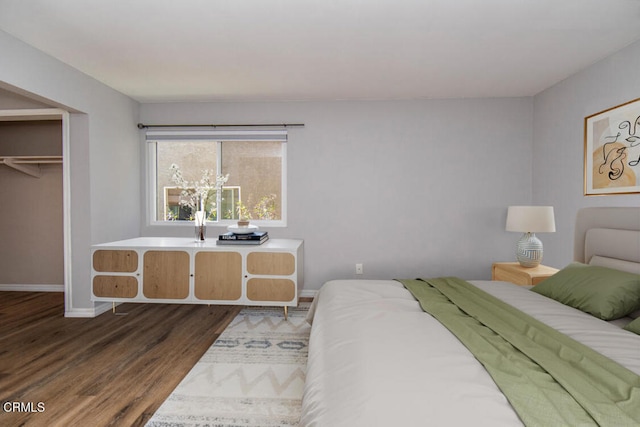 bedroom featuring a spacious closet, a closet, and dark hardwood / wood-style flooring