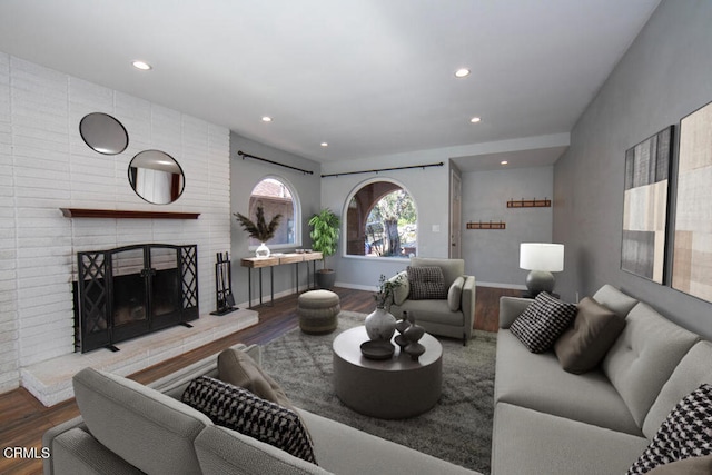 living room with a brick fireplace and hardwood / wood-style flooring