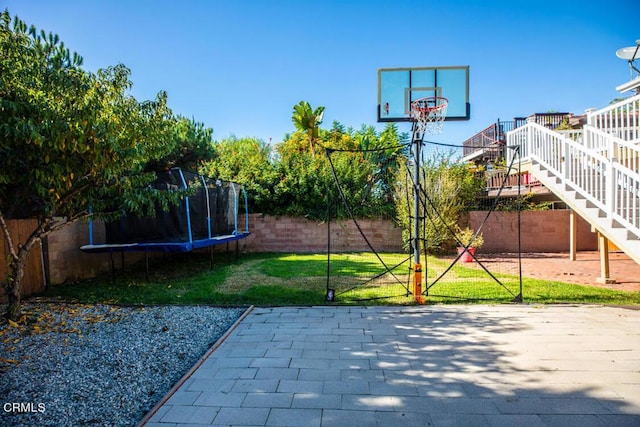 view of basketball court featuring a trampoline and a lawn