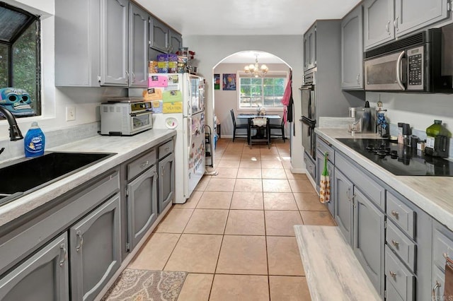 kitchen with gray cabinetry, sink, light tile patterned floors, and black appliances