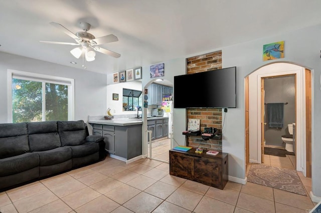 tiled living room with ceiling fan and sink