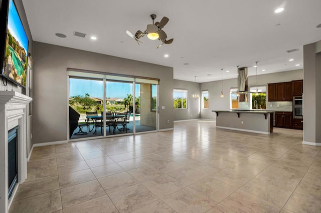 unfurnished living room featuring sink, light tile patterned floors, and ceiling fan