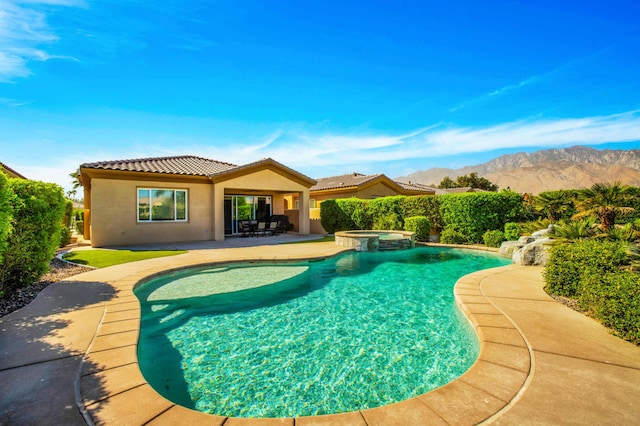 view of swimming pool with a patio area, a mountain view, and an in ground hot tub