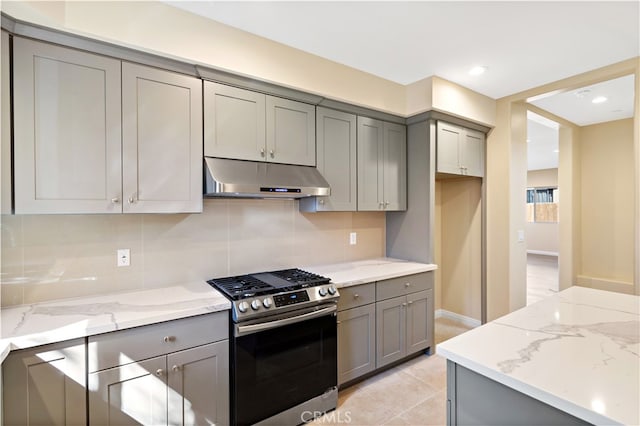 kitchen featuring light stone counters, gas stove, decorative backsplash, and gray cabinets