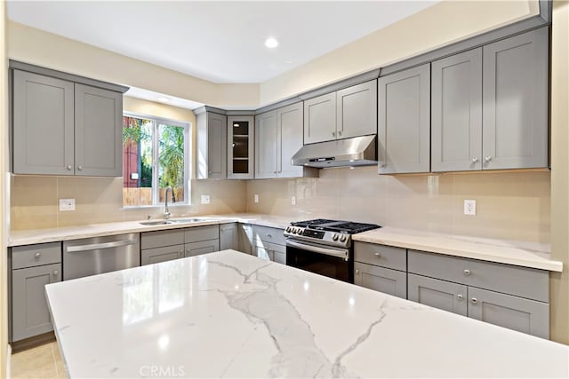 kitchen featuring sink, appliances with stainless steel finishes, light stone counters, and gray cabinetry