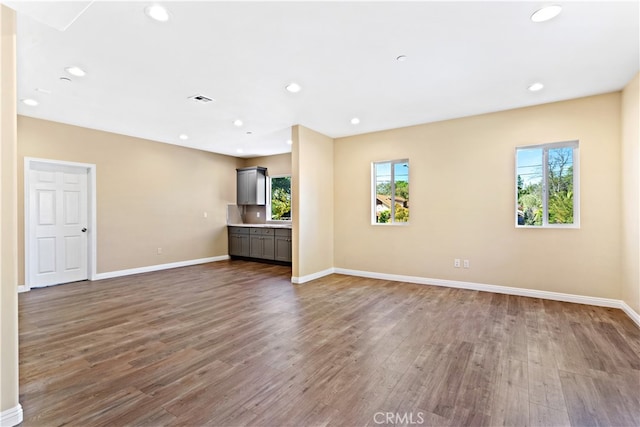 unfurnished living room with dark hardwood / wood-style flooring and a wealth of natural light