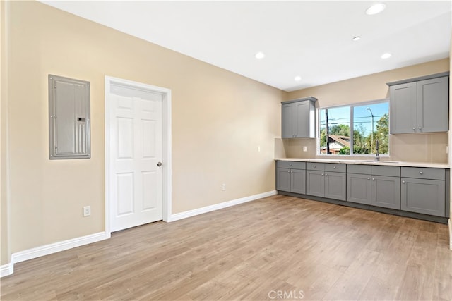 kitchen featuring gray cabinets, sink, electric panel, and light hardwood / wood-style floors