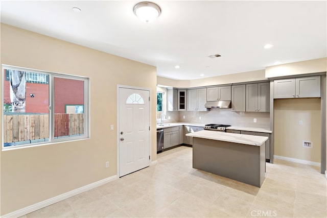 kitchen featuring light stone countertops, sink, a center island, stainless steel appliances, and gray cabinets