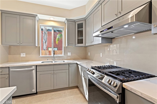 kitchen with backsplash, stainless steel appliances, sink, and light tile patterned flooring