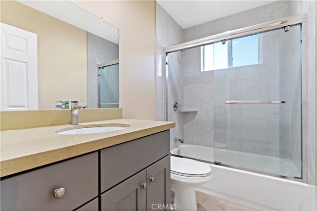 full bathroom with vanity, bath / shower combo with glass door, and toilet