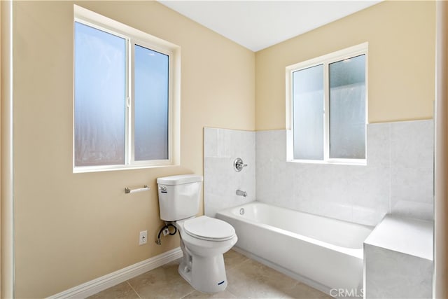 bathroom with a tub to relax in, tile patterned floors, and toilet