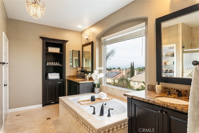 bathroom featuring vanity, tile patterned floors, an inviting chandelier, and tiled tub