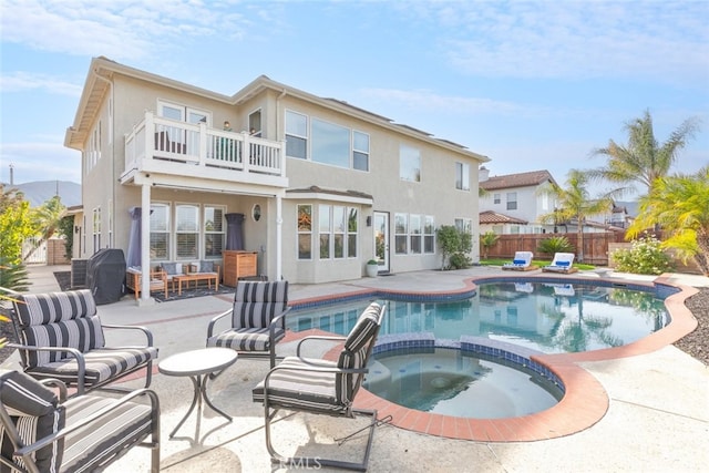 back of house featuring a balcony, a pool with hot tub, and a patio