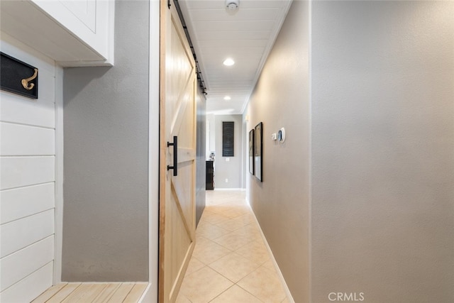 corridor featuring a barn door, light tile patterned floors, and crown molding