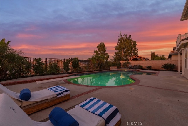 pool at dusk with a patio area