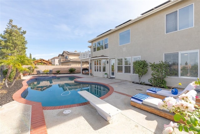 view of swimming pool featuring a diving board and a patio