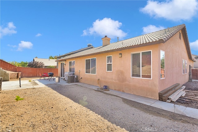 back of property with central air condition unit and a patio area