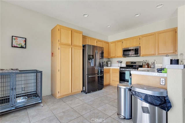 kitchen featuring tile countertops, appliances with stainless steel finishes, light tile patterned floors, and light brown cabinets