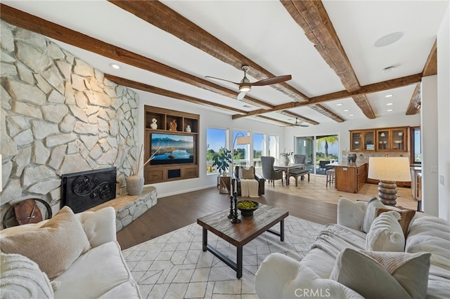 living room featuring light hardwood / wood-style flooring, beamed ceiling, and ceiling fan