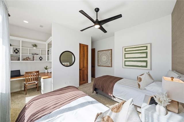 carpeted bedroom with built in desk and ceiling fan