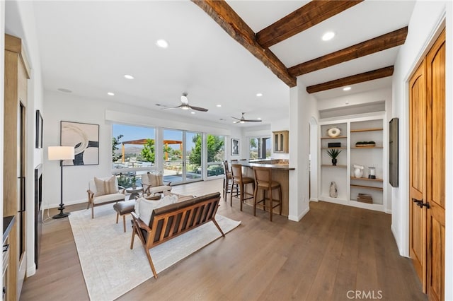 living room with beam ceiling, light wood-type flooring, and ceiling fan