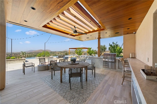 view of patio / terrace featuring exterior kitchen, a mountain view, grilling area, and ceiling fan