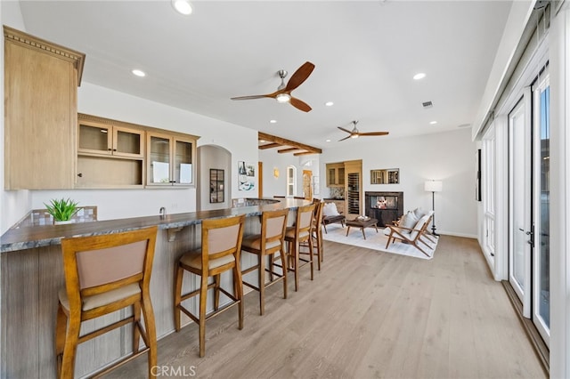 kitchen featuring a breakfast bar area, kitchen peninsula, light wood-type flooring, light brown cabinetry, and ceiling fan