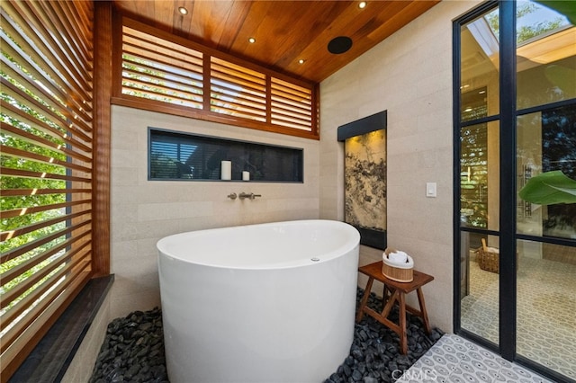 bathroom with tile walls, wood ceiling, and a washtub