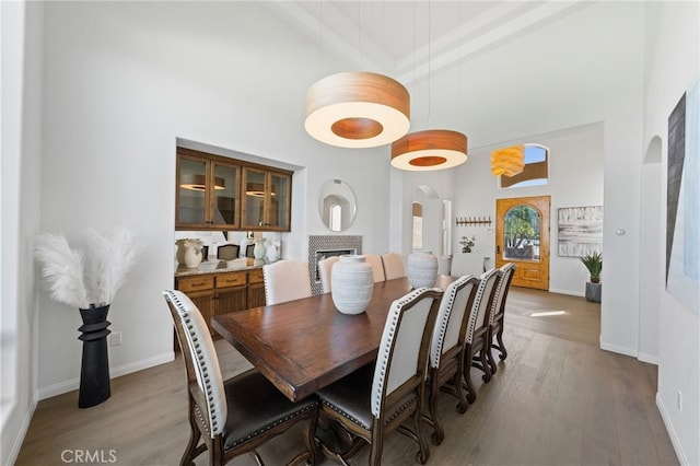 dining space with a high ceiling, a fireplace, and light hardwood / wood-style floors