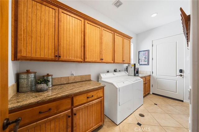 laundry room with washer and dryer, cabinets, and light tile patterned floors