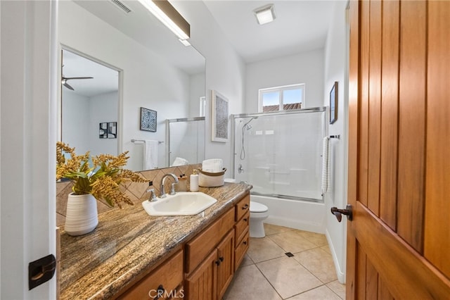 full bathroom featuring ceiling fan, bath / shower combo with glass door, toilet, vanity, and tile patterned floors