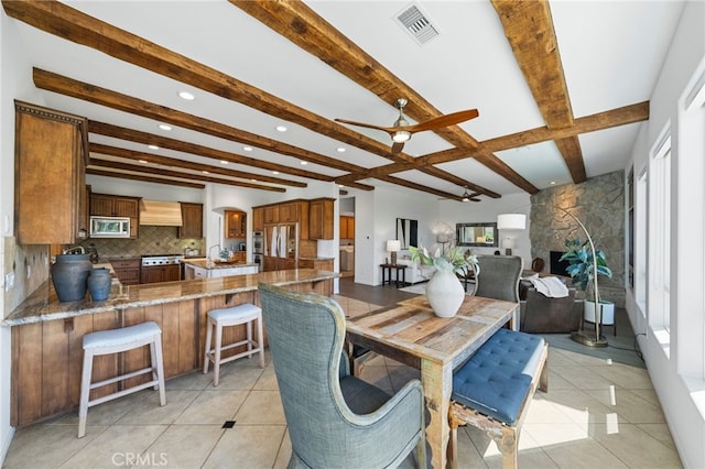 dining space featuring beam ceiling, light tile patterned floors, and ceiling fan